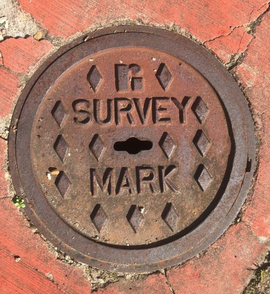 Photo: "Photo:Steel or concrete covers installed at ground level, with the actual survey mark located underneath